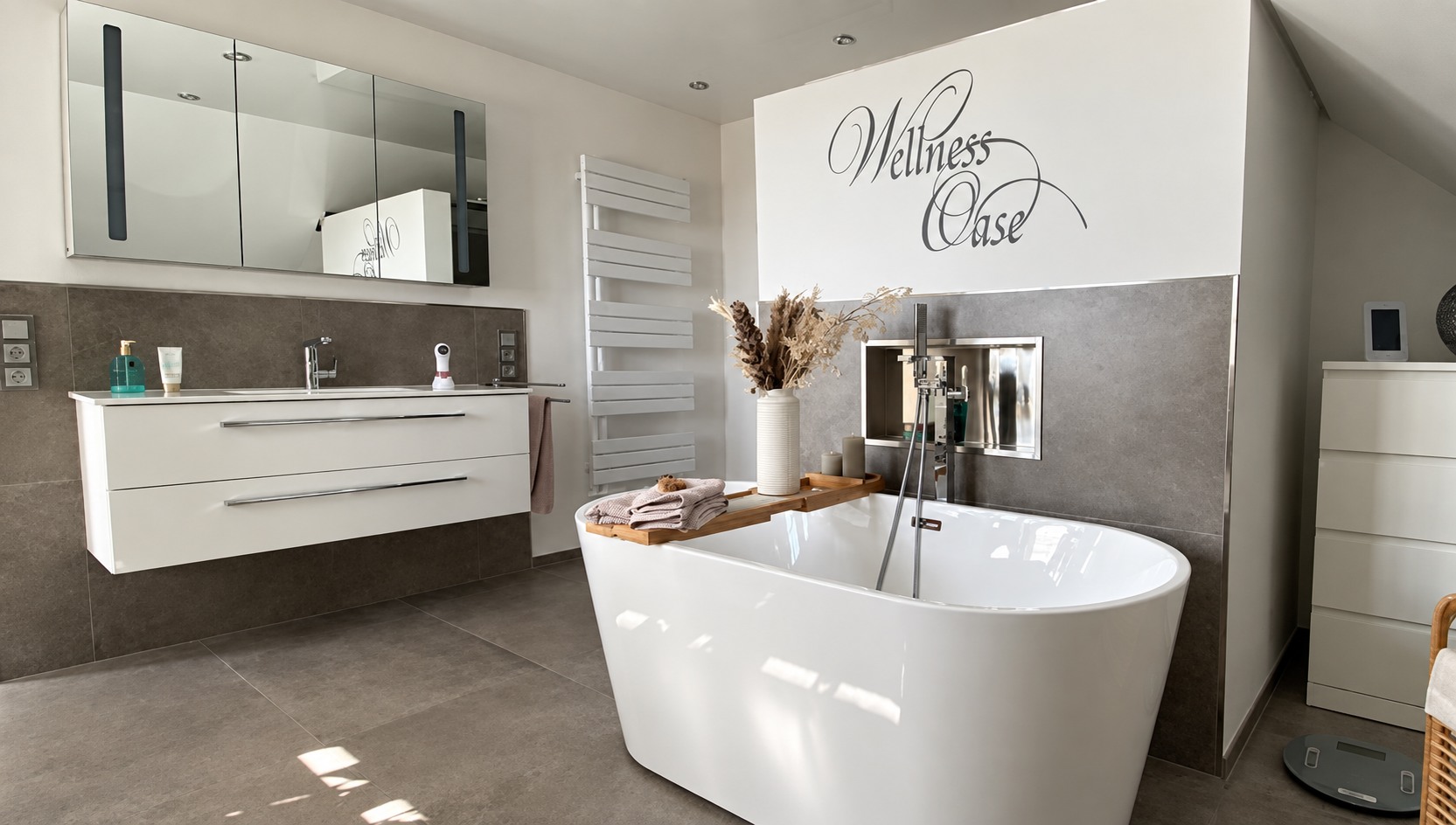 Badezimmer mit freistehender Badewanne, großformatigen Fliesen und beleuchteter Wandnische